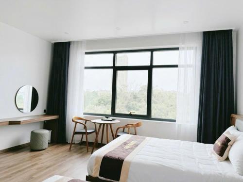a bedroom with a bed and a table and a window at Long Hải Hotel in Móng Cái