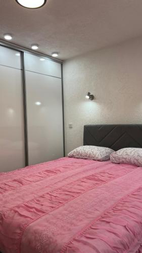a bedroom with a large bed with a pink blanket at Behar Apartment with City View in Sarajevo