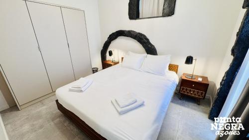 a bedroom with a large white bed with white towels on it at O Palheiro in Biscoitos