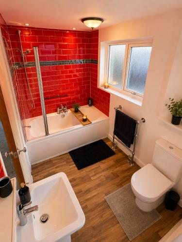 a bathroom with a white tub and a red brick wall at Westbrook Spacious 3 Bed in Exeter in Pinhoe