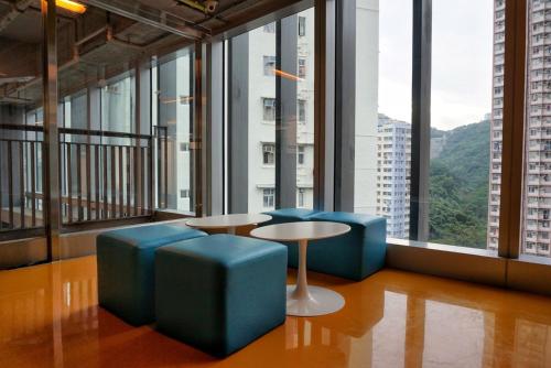 a room with blue chairs and a table and windows at Y Loft in Hong Kong