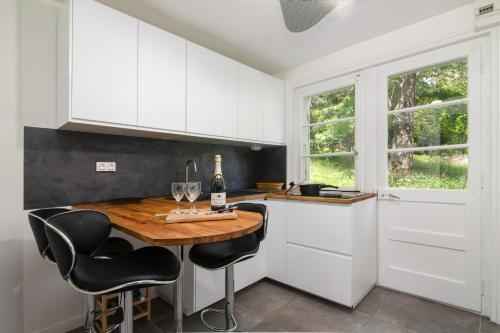 a kitchen with white cabinets and a wooden table with wine glasses at Chalet Ecureuil Family retreat w/ Garden & Fireplace - Happy Rentals in Chamonix