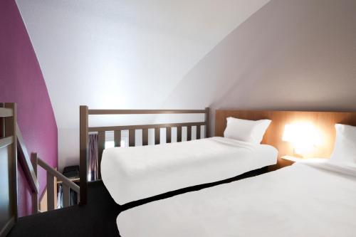 two beds sitting next to each other in a room at B&B HOTEL Lyon Vénissieux in Vénissieux