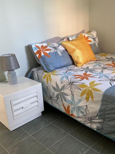 a bed with colorful pillows and a table with a lamp at las gaviotas in Bayahibe