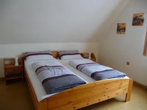 a wooden bed with four pillows on it in a room at Ferienwohnung Wassergartenparadies in Harsdorf