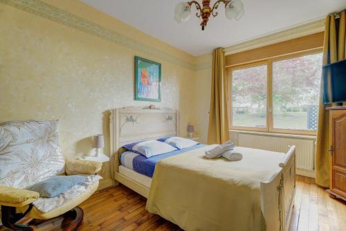 a bedroom with a bed and a chair and a window at La maison de la Rebergère in Javené