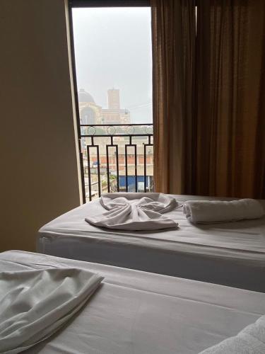 a bed with white sheets and a window with a view at Basilica Palace Hotel in Aparecida
