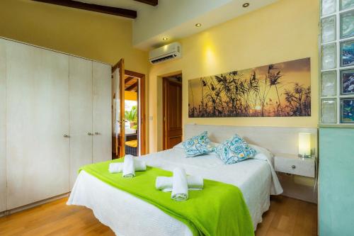a bedroom with a large bed with a green blanket at Can Magraner in Port de Pollensa
