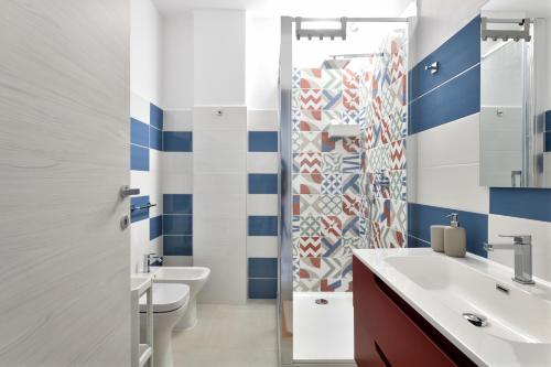 a bathroom with blue and white walls and a toilet and sink at Appartamentino in Bari Sardo