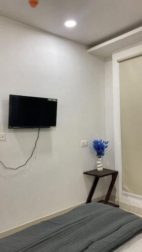 a room with a tv on a wall with a table at The Horizon Blue in Zirakpur