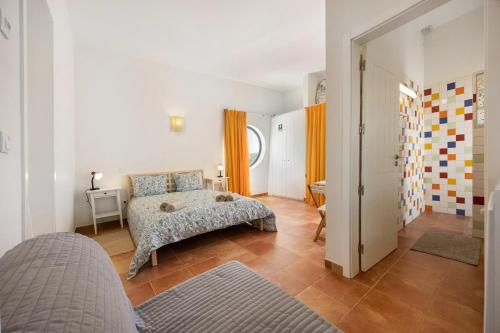 a bedroom with a bed and a hallway with orange curtains at Amado Properties in Carrapateira