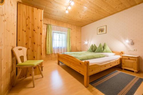 a bedroom with a bed and a chair in a cabin at Obermarhof Gsies in Prateria