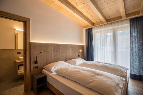 a bedroom with a bed with white sheets and a window at App. Pedagà - Ciasa Lavarella in San Vigilio Di Marebbe