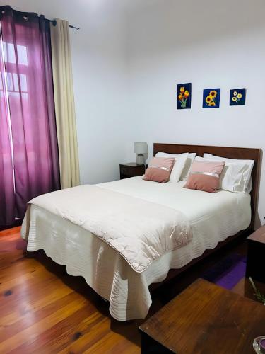 a bedroom with a large white bed with pink pillows at Garden View Apartment in Horta
