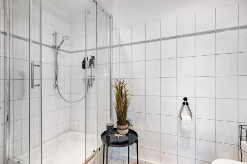 a bathroom with a shower and a plant on a stool at Ferienwohnung Clara in Bremerhaven