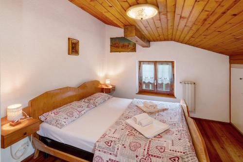 a bedroom with a large bed with a wooden ceiling at Appartamento Palmina in Falcade