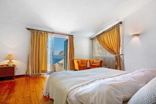a bedroom with a bed and a large window at Bela Vigia in Jardim do Mar
