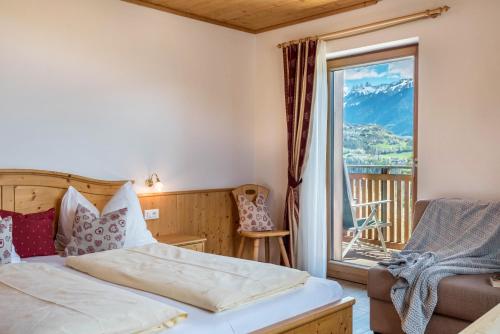 a bedroom with a bed and a balcony with a view at Huberhof Appzimmer in Feldthurns