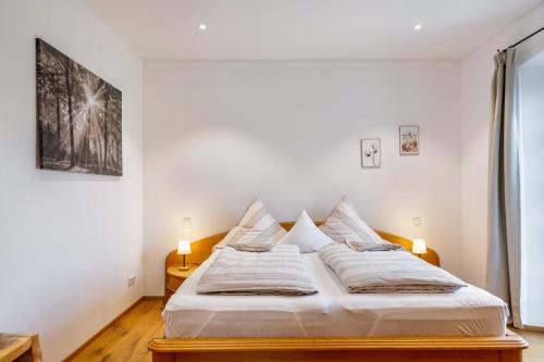 a bedroom with a bed with white sheets and pillows at Ferienwohnung z'Dandlberg in Tittmoning