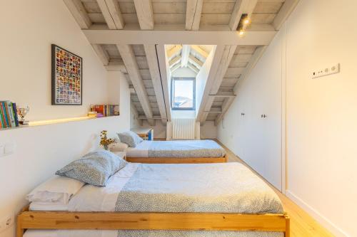 two beds in a attic bedroom with a window at Rio Tío Cocinas in La Granja de San Ildefonso