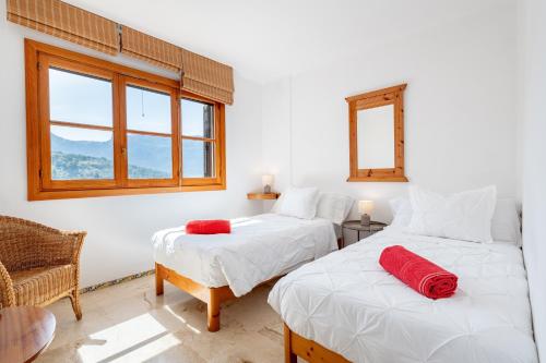 two beds in a room with a chair and a window at Montemar 36 in Port de Soller