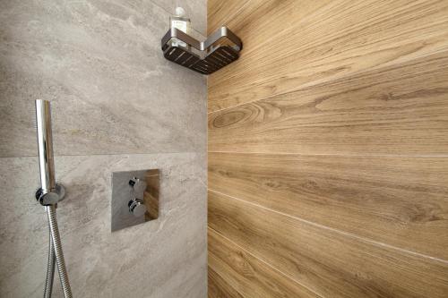 a shower in a bathroom with a wooden wall at Dolomiti e Misurina My dreams in Misurina