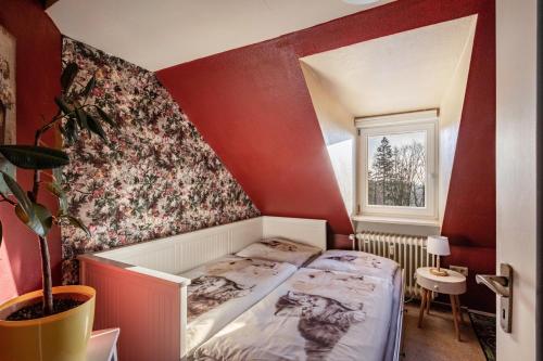 a bedroom with a bed in a red wall at Das Spatzennest in Bad Sachsa