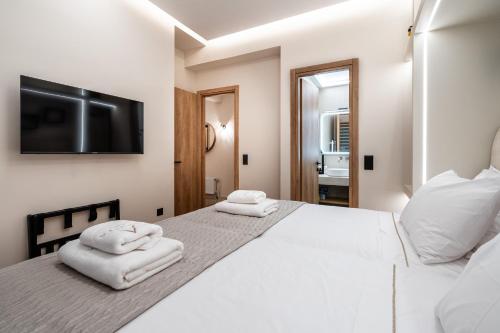 a white bedroom with a large bed with towels on it at The Apex Boutique Apartment B1 in Athens