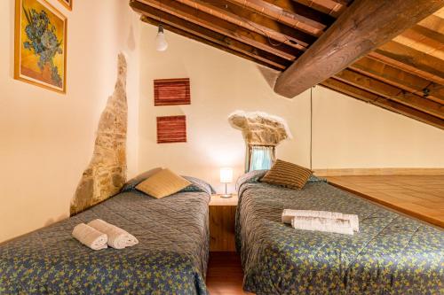 two twin beds in a room with wooden floors at Il Colletto Romantic Stonehouse in Pescia