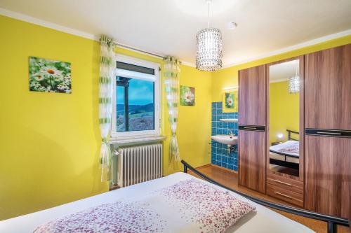 a yellow bedroom with a bed and a window at Haus Loks in Sankt Märgen
