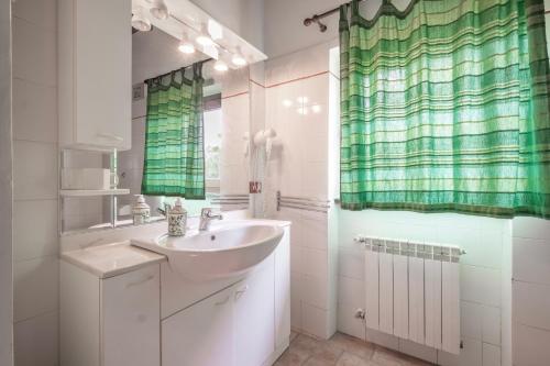 a bathroom with a sink and a green shower curtain at Casaletto della musica in Viterbo