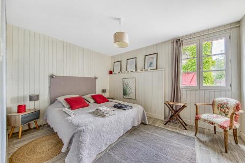 a bedroom with a bed with red pillows and a chair at Échappée Bel in Arveyres