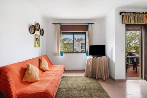 a living room with an orange couch and a window at Beach House-5 Minutos a pé da praia in Manta Rota