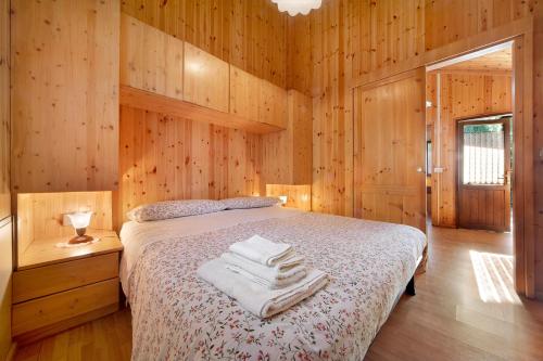 a bedroom with wooden walls and a bed with towels on it at Casa Ciclamino in Barzio