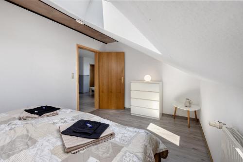 a white bedroom with a bed and a table at Ferienwohnung Thomée in Looft