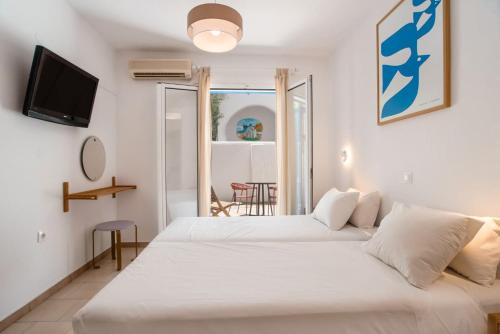 a bedroom with two beds and a tv on the wall at Adelfia Studios in Parikia