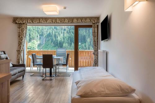 a bedroom with a bed and a table and chairs at Garni Hotel Gardena App Dolomites 3 in Santa Cristina Gherdëina