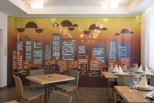 a restaurant with tables and chairs and a mural of a city at HOTEL A RESTAURACE U STAVAŘE in Vsetín