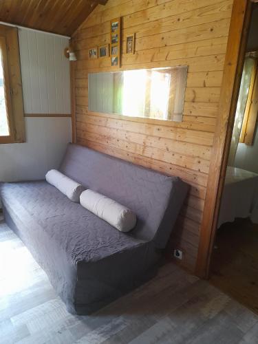 a bed in a room with a wooden wall at Chalet Dominique in Azzana