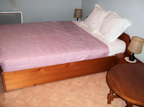a bed with a wooden frame and a wooden table at Le Paillassou in Blanzac