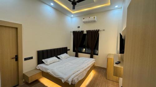 a bedroom with a bed and a flat screen tv at iv hotel Ajmer in Madār