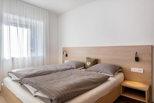 a bedroom with a large bed with a wooden headboard at Mountain Meadows Apt 1 in Valdaora