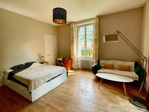 a bedroom with a bed and a couch and a window at Villa Isabelle in Allevard