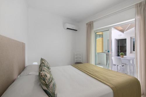 a bedroom with a bed and a balcony with a table at Refúgio Estrela do Mar in Quarteira