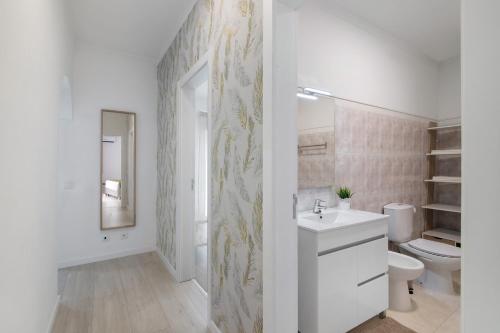a white bathroom with a sink and a toilet at Refúgio Estrela do Mar in Quarteira