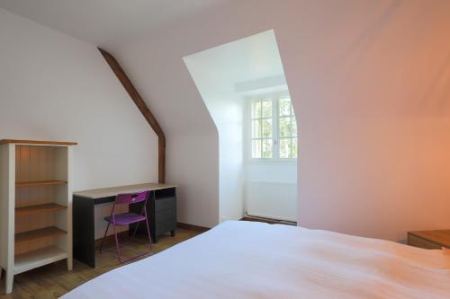a bedroom with a bed and a desk and a window at Les Camelias in Locquirec