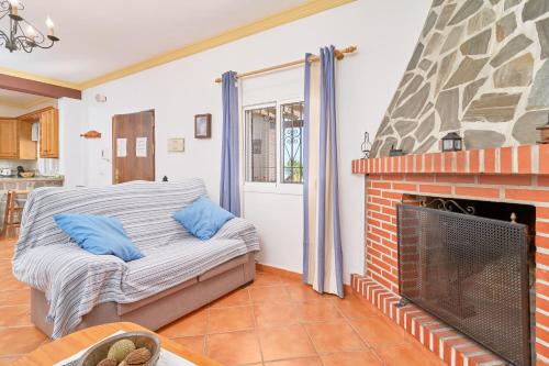 a living room with a brick fireplace with blue pillows at Villa El Peli in Nerja