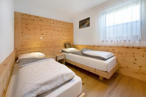 two beds in a room with wooden walls at Teutenhofer Kastanie in Feldthurns