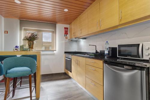 a kitchen with wooden cabinets and a blue chair at Casa Da Capela in Entre Ambos os Rios