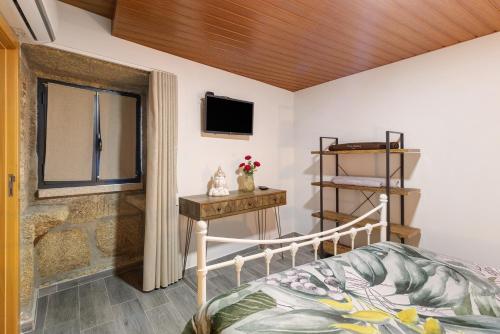 a bedroom with a bed and a window and a tv at Casa Da Capela in Entre Ambos os Rios